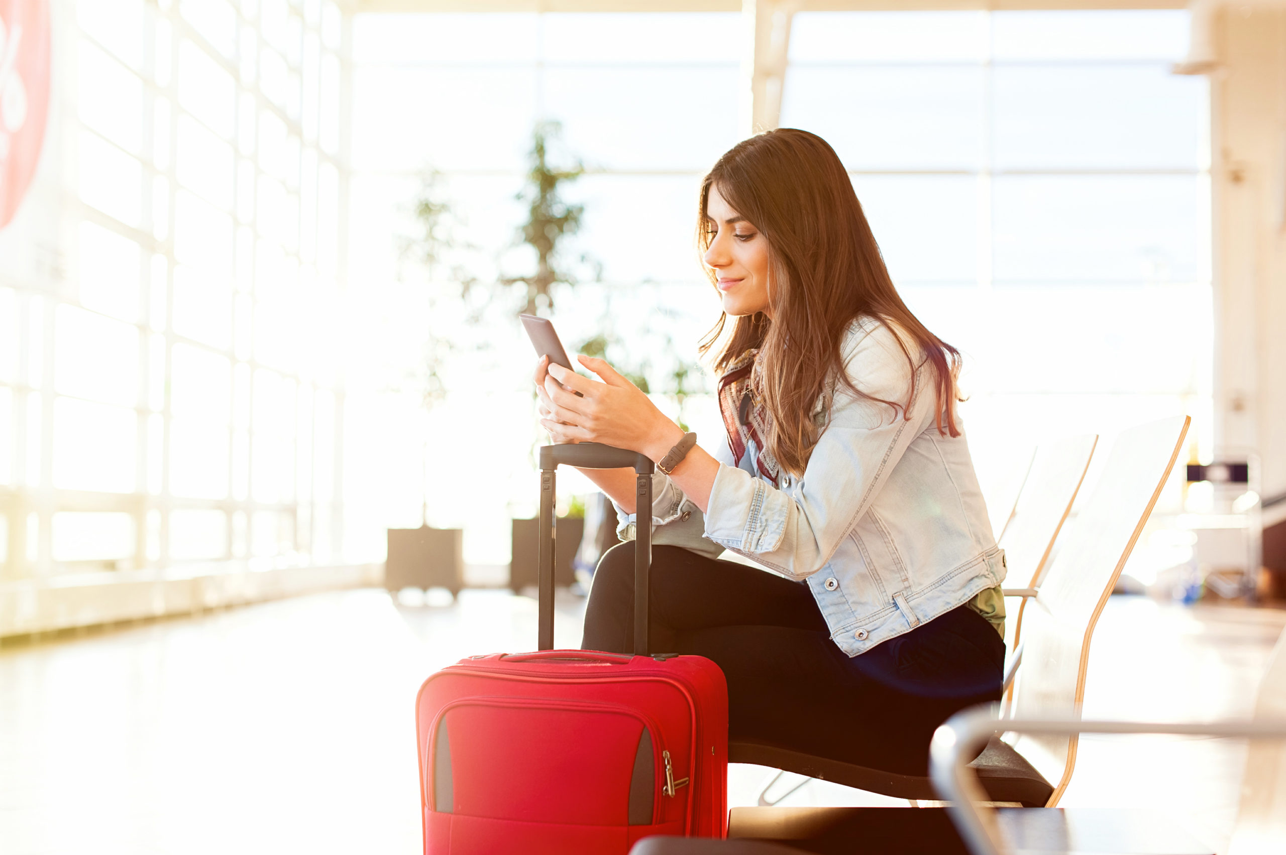 woman waiting in airport with luggage, phone, holiday traveling